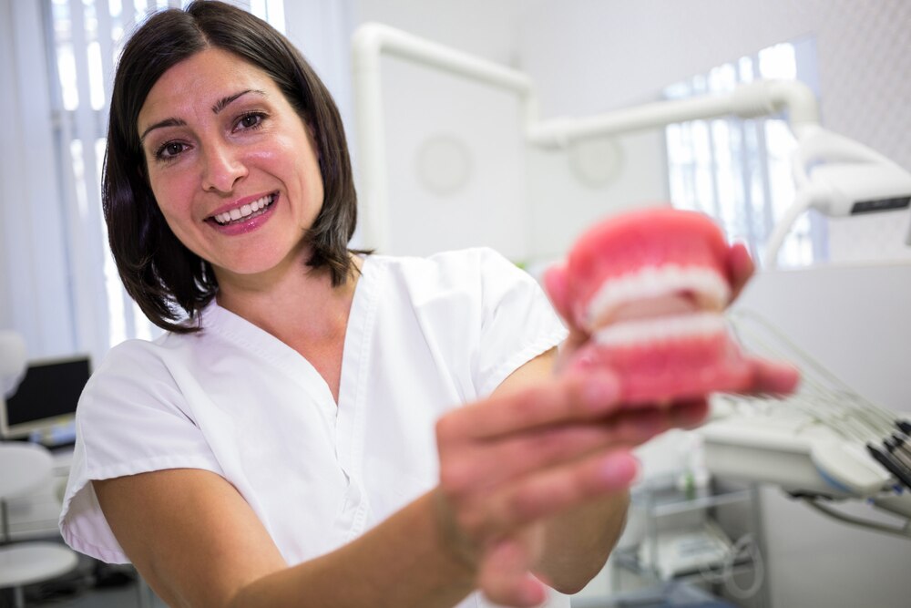 Portrait of female dentist holding a set of dentures